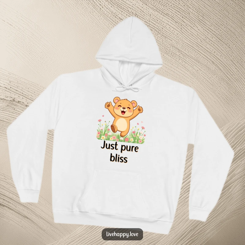 Funny hoodie showing a cute bear cub leaping with joy amidst a field of bright, blooming flowers, feeling utterly happy.